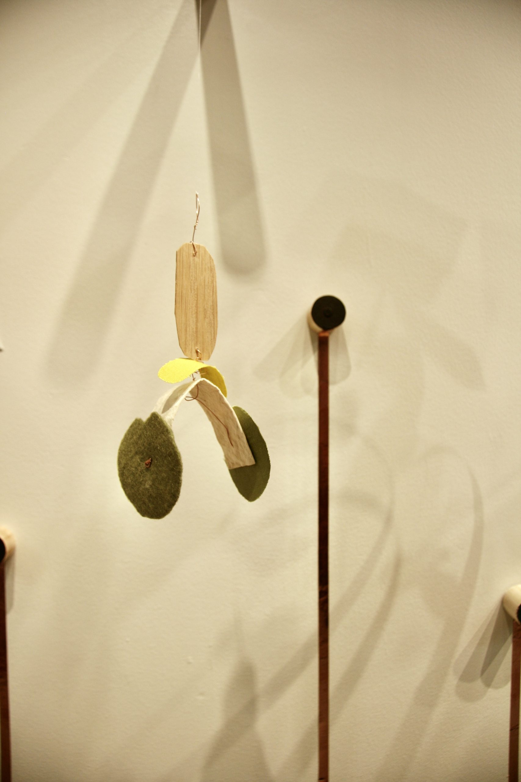 A detail of one mixed-media sculpture in the shape of a canopy with a black sound-activated dowel in the background.