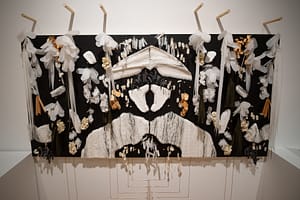 Two black panels mirroring each other in an Inkblot shape with various mixed-media sculptures and a layered texture, similar to Scales, in an organic design.
