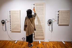 An image of a visitor interacting with the audio translation of the Soft-Spoken series.