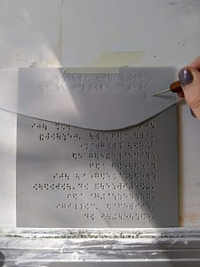 Embossing the Braille with a stylus on Dura-lar-film.