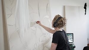 A photo of myself drawing on a large canvas in The Cotton Factory studio.
