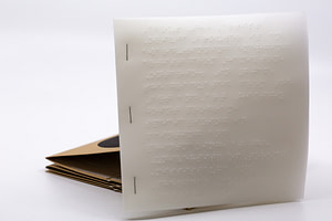 Image description: A small, square Braille booklet included with the accordion book as the translation for the instructions at the beginning of the book.