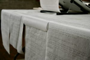 Braille traced on sheets of tracing paper which are cascading over a table.